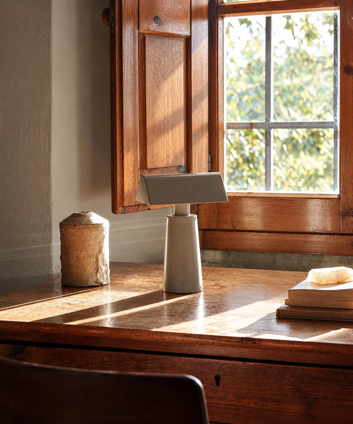 Petite lampe de table gris clair sur un bureau en bois, près d’une fenêtre