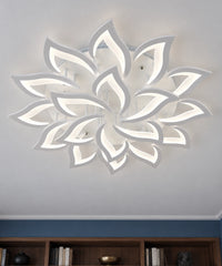 Plafonnier fleur de lotus blanc à pétales ajourés, vu de dessous près d’une bibliothèque