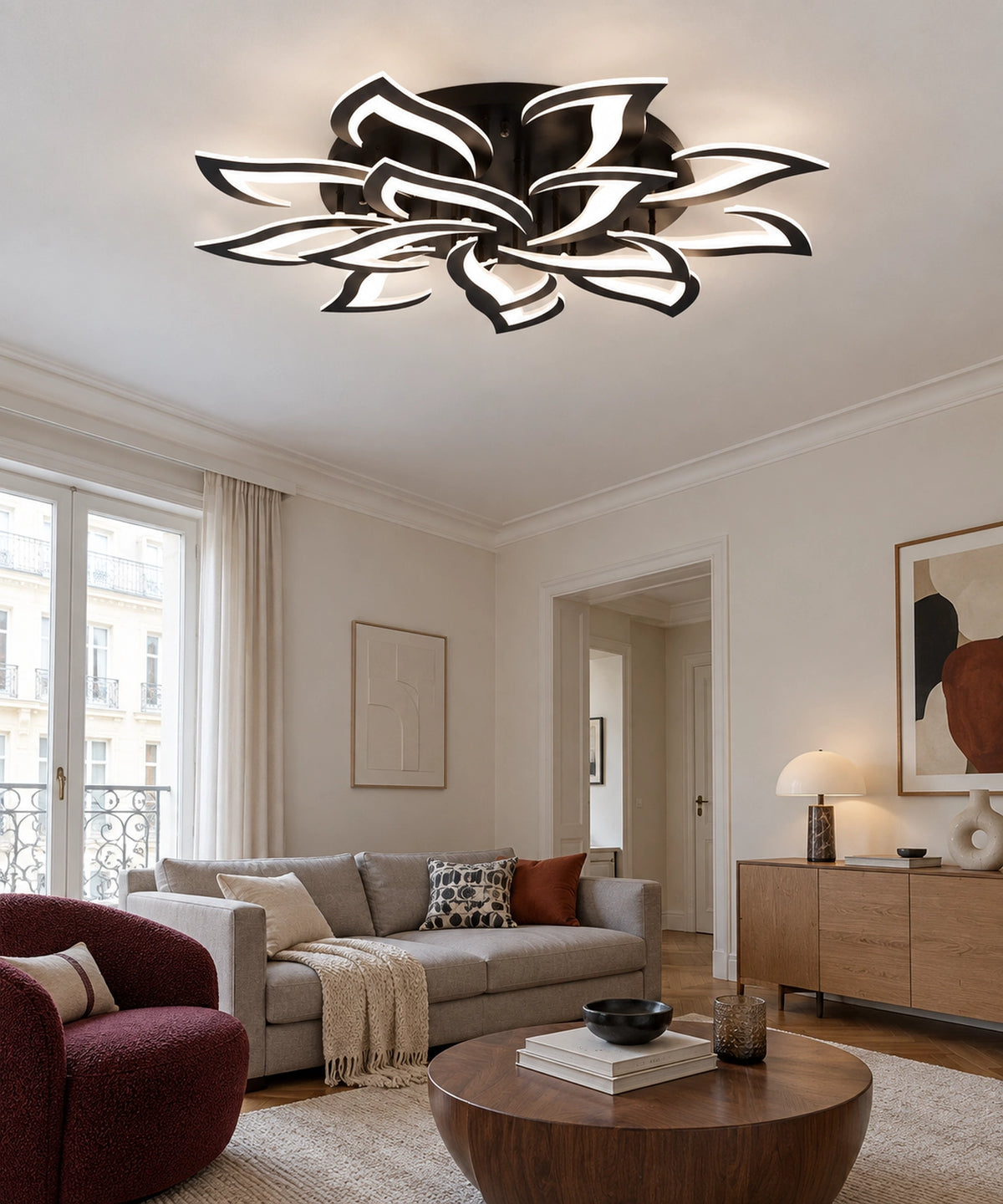 Plafonnier lotus noir allumé dans un salon avec canapé beige et fauteuil bordeaux