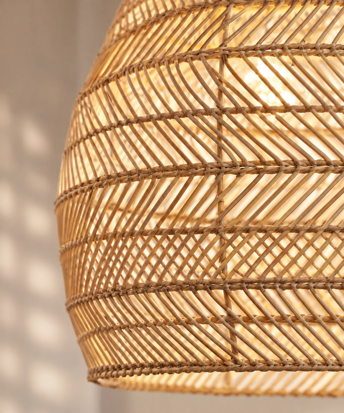 Gros plan du tressage diagonal et des cerclages de la suspension cloche en rotin beige