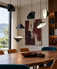 Six suspensions LED noires à cônes orientables, dans différentes positions, au-dessus d’une table en noyer.