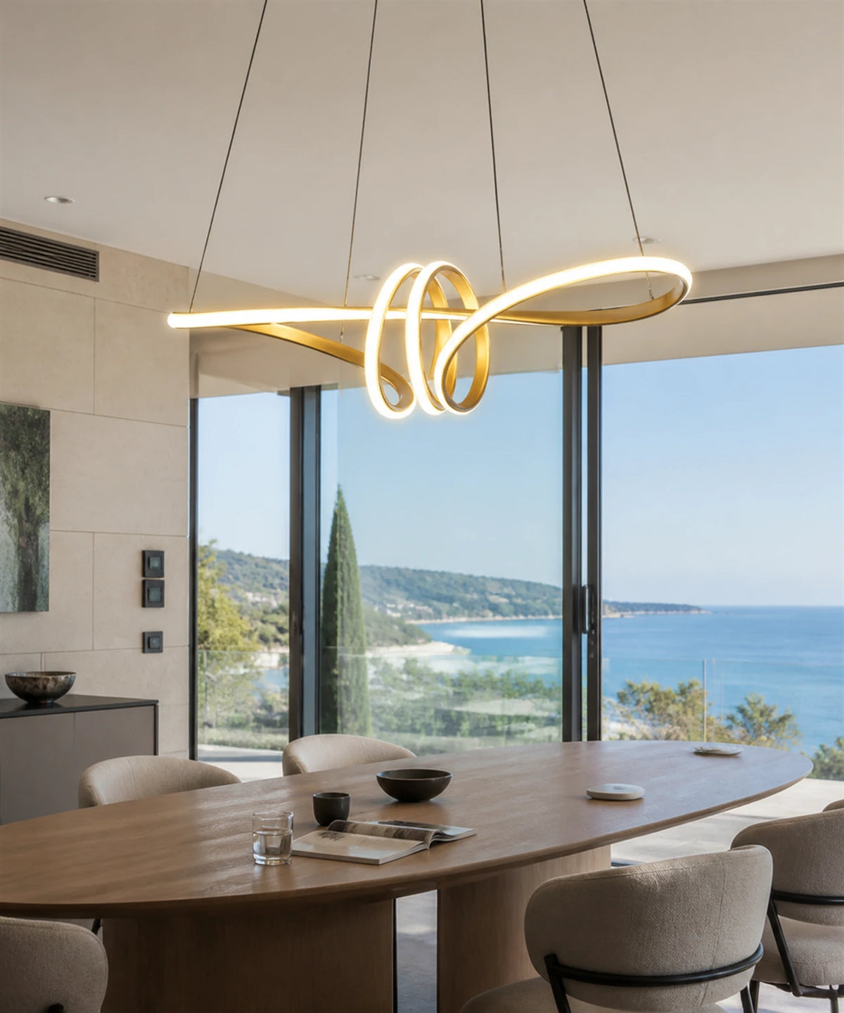 Suspension LED ruban doré allumée dans une salle à manger de villa face à la mer