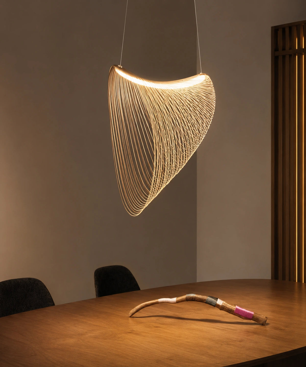 Suspension en lamelles de hêtre cintrées allumée au-dessus d’une table en bois Image