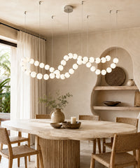 Suspension luminaire boules à connecteurs argentés au-dessus d’une table entourée de chaises en cannage