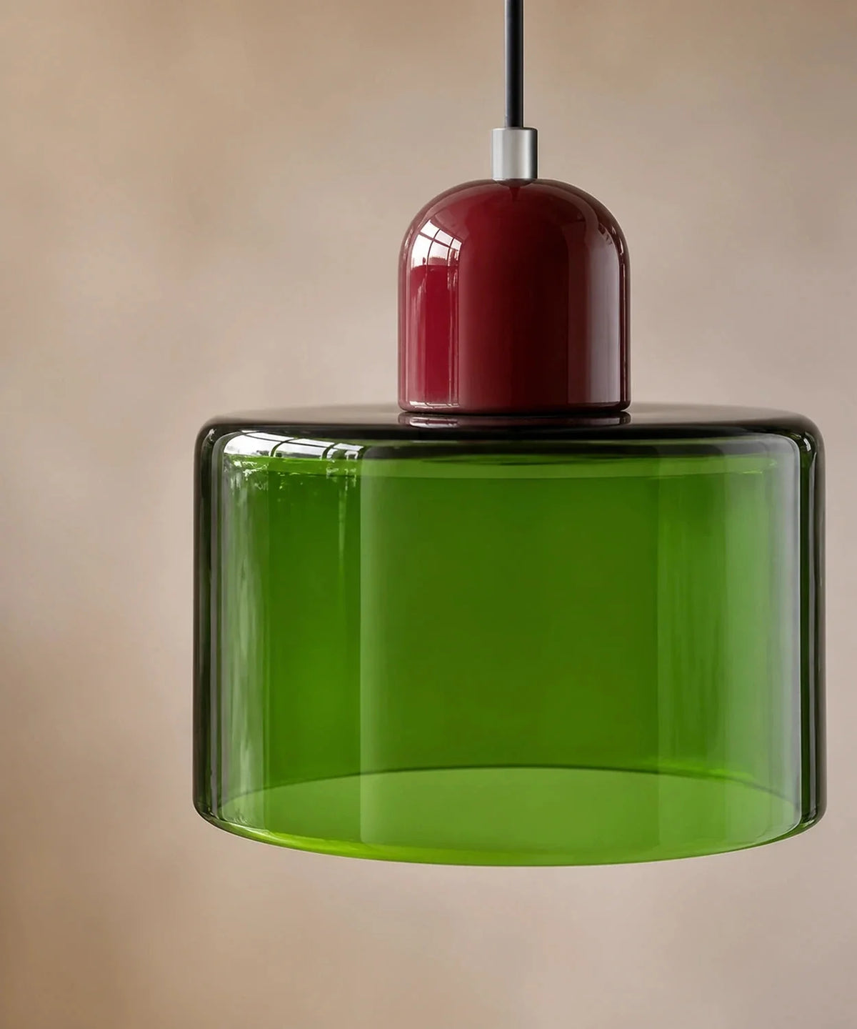 Gros plan sur le cylindre de verre vert transparent et son culot bordeaux laqué