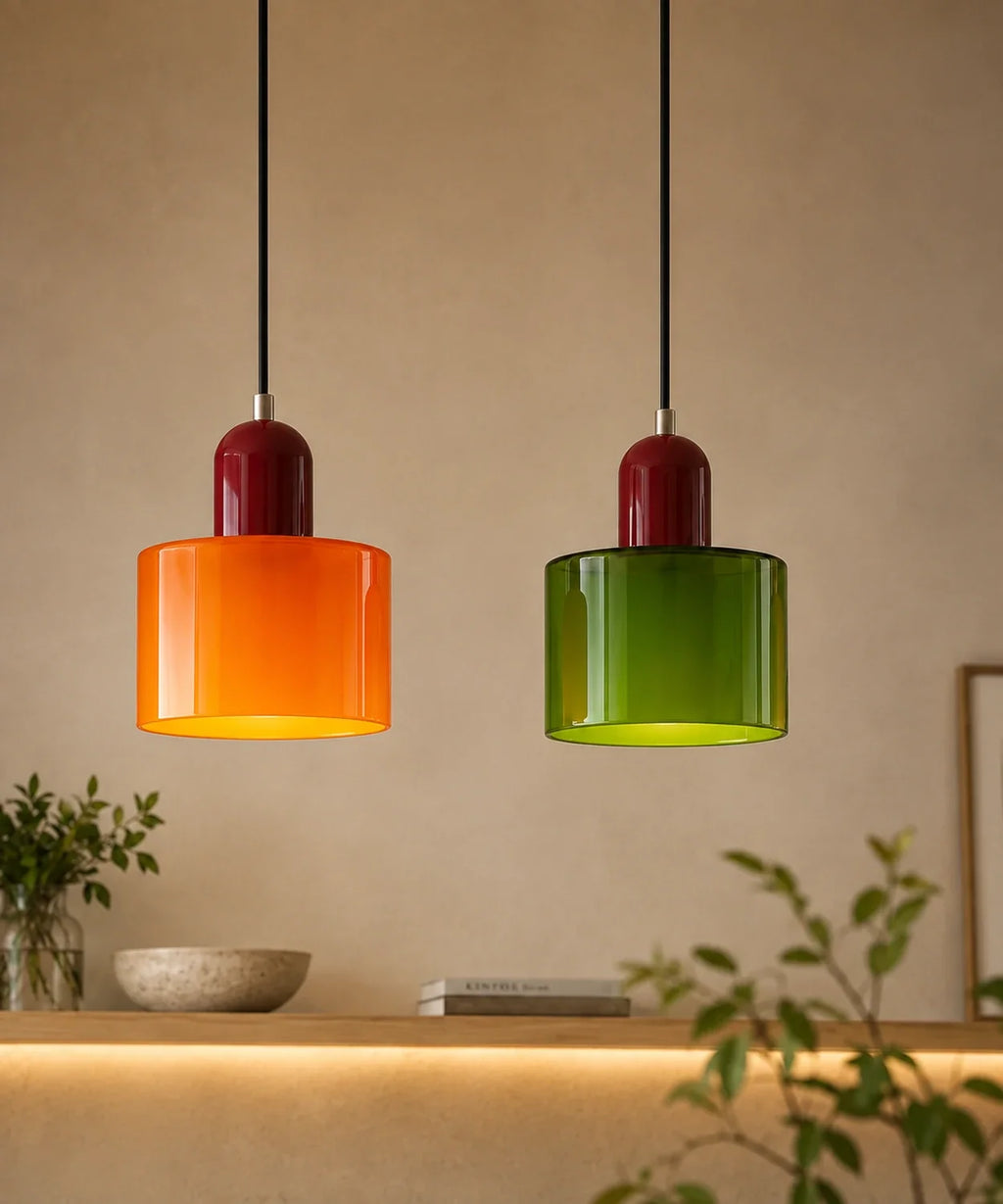 Deux suspensions cylindre en verre orange et vert allumées au-dessus d’une console en chêne