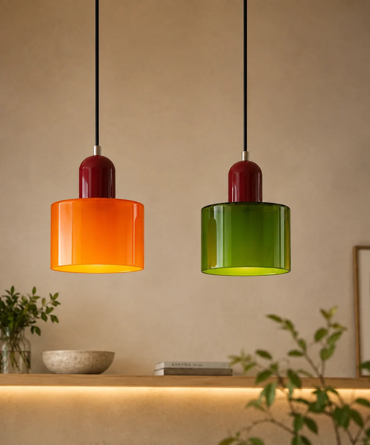 Deux suspensions cylindre en verre orange et vert allumées au-dessus d’une console en chêne