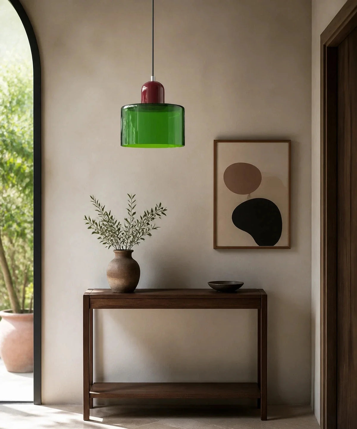 Suspension cylindre en verre vert et culot bordeaux au-dessus d’une console d’entrée en noyer