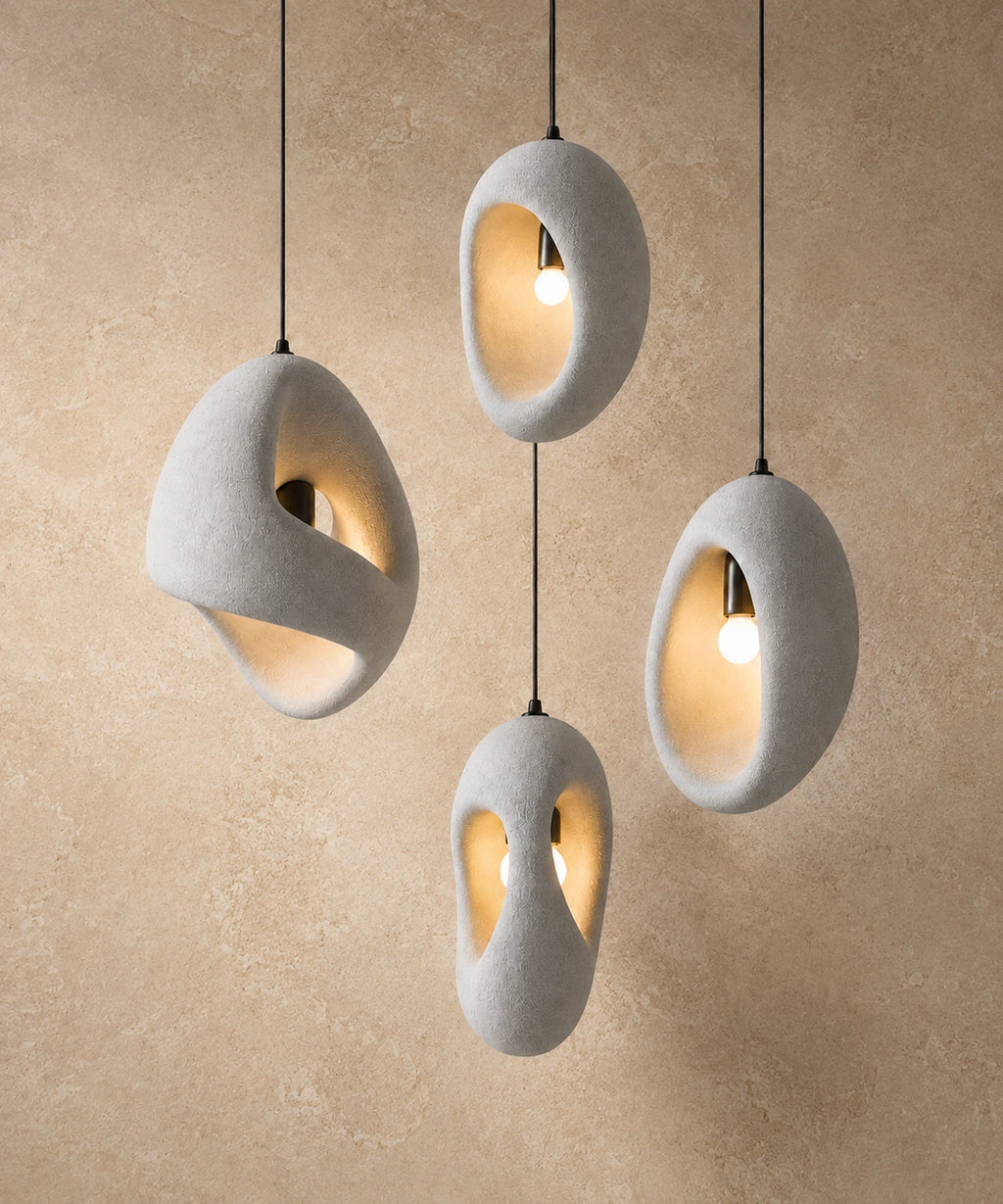 Suspension luminaire galet, ensemble de quatre galets blancs allumés devant un mur enduit