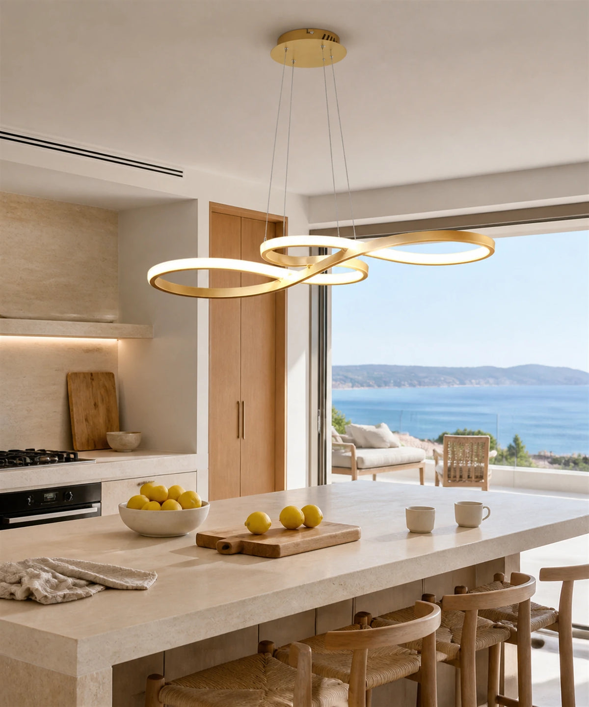 Suspension LED en boucle infinie dorée allumée au-dessus d’un îlot de cuisine face à la mer Image