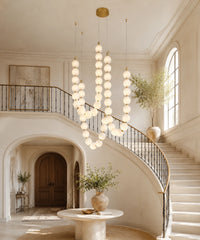 Suspension luminaire perles à trois brins devant un escalier courbe à rampe noire