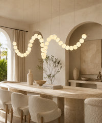 Guirlande de boules opalines à boucle, connecteurs dorés, entre deux arches au-dessus d’une table