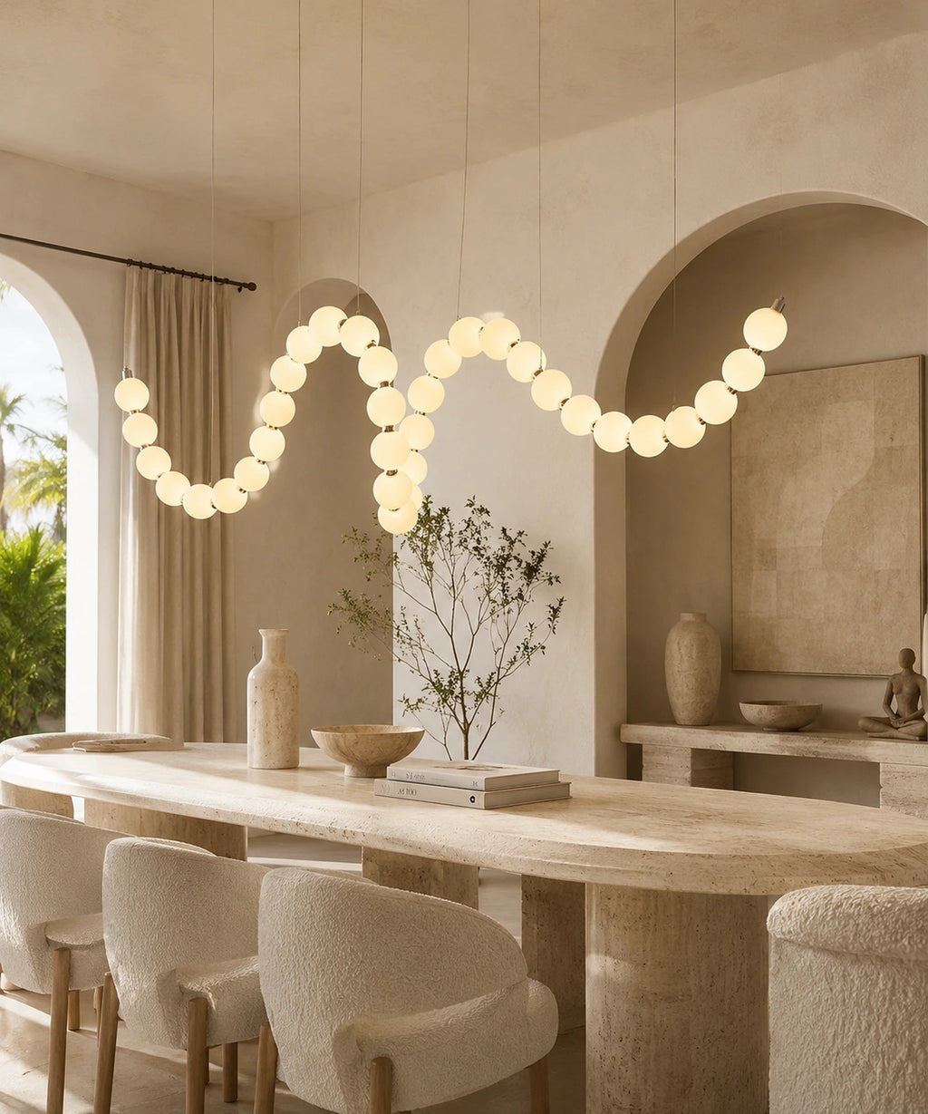Suspension à boules opalines serpentant au-dessus d’une table en travertin, murs enduits