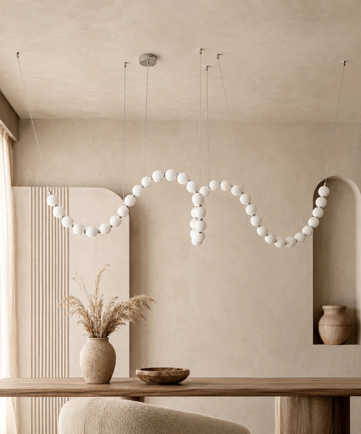 Suspension luminaire plusieurs boules argentée de 200 cm serpentant au-dessus d’une table