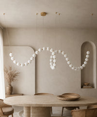 Suspension luminaire plusieurs boules dorée de 200 cm serpentant dans une salle à manger
