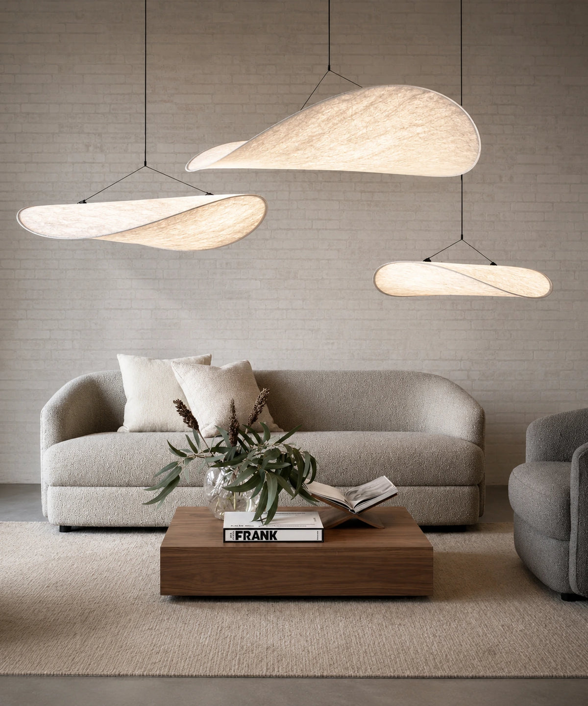 Suspension luminaire tissu blanc, trois voiles allumées à hauteurs décalées au-dessus d’un salon
