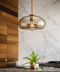 Suspension luminaire verre champagne en galet devant une crédence en marbre et un mur de bois