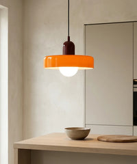 Suspension en verre coloré orange allumée au-dessus d’un plan de travail en chêne