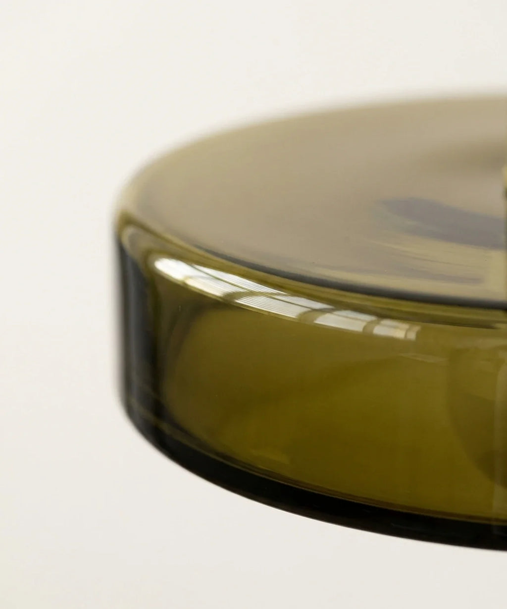 Gros plan sur la tranche du disque de verre vert olive, surface lisse et brillante