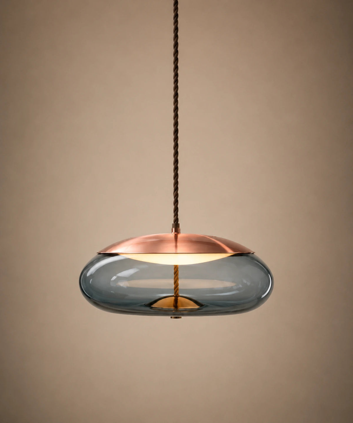 Suspension galet en verre soufflé bleu, capuchon cuivré, allumée sur fond beige