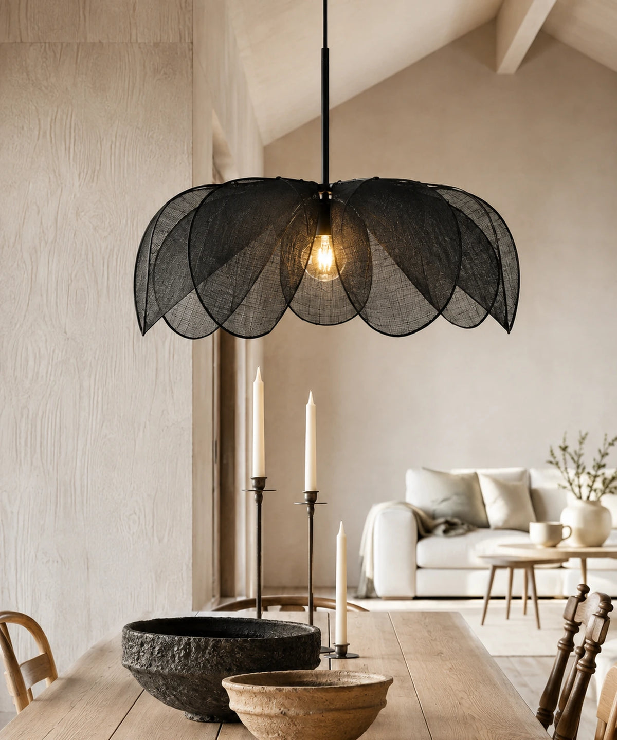 Suspension pétales de tissu plissé noir allumée au-dessus d’une table, bougeoirs