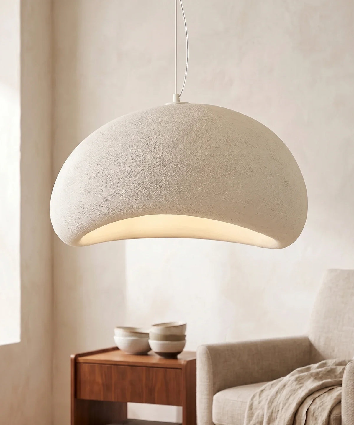 Suspension wabi sabi galet blanche galet fermé allumée près d un fauteuil en lin