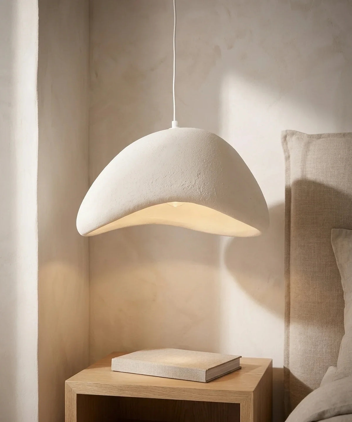 Suspension wabi sabi galet blanche allumee au-dessus d une table de chevet en chene